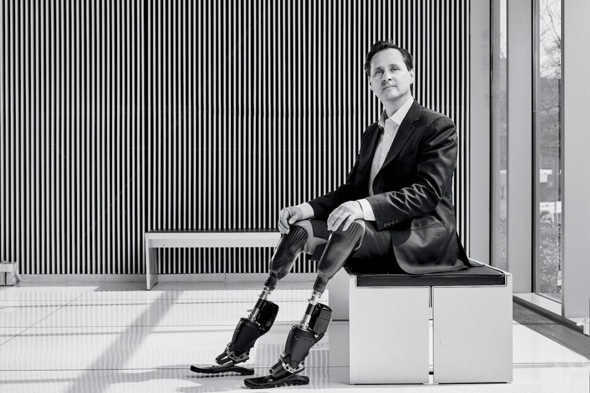 Professor Hugh Herr seated, wearing two lower-leg prostheses