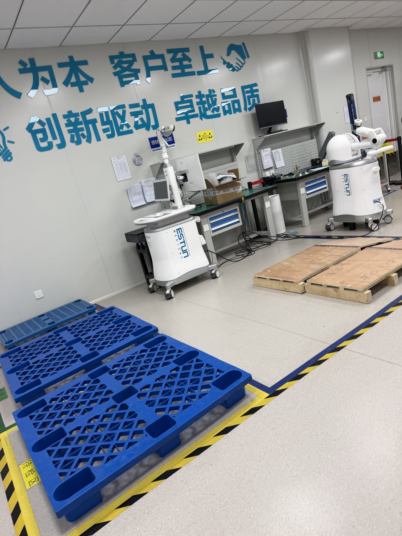 Medical robotic arms on mobile bases beside workshop benches